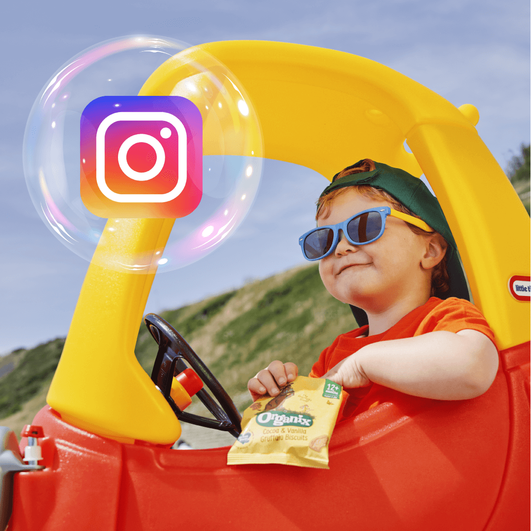 A child in a toy car, holding a bag of Organix snacks. Also the Instagram logo inside an Organix Lil' Ballers bubble.